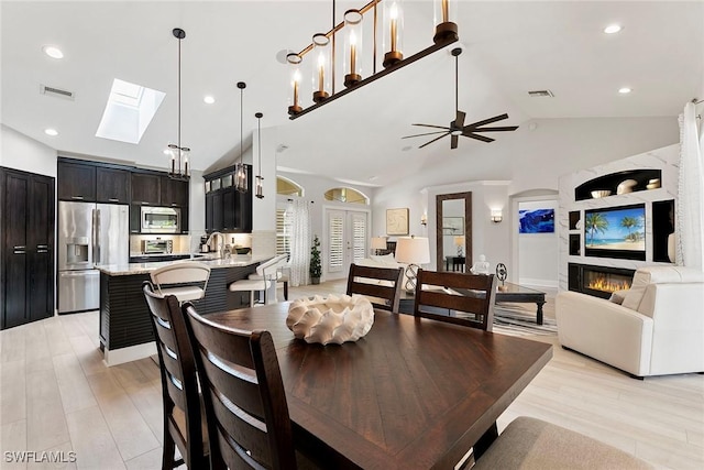 2322 River Reach Dr, Naples, FL 34104 - dining room with a skylight, recessed lighting, a ceiling fan, a glass covered fireplace, and light wood-style floors