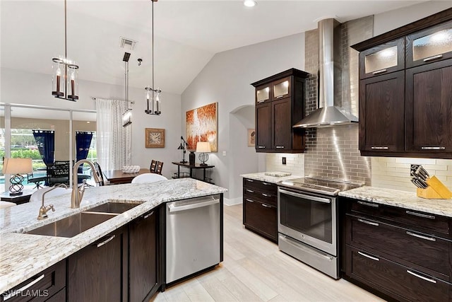 2322 River Reach Dr, Naples, FL 34104 - kitchen with wall chimney exhaust hood, appliances with stainless steel finishes, tasteful backsplash, light wood-style floors, and lofted ceiling