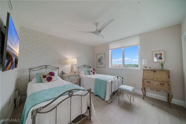7515 Pelican Bay Blvd Unit 8A, Naples, FL 34108 - bedroom with wallpapered walls, ceiling fan, wood finished floors, and an accent wall