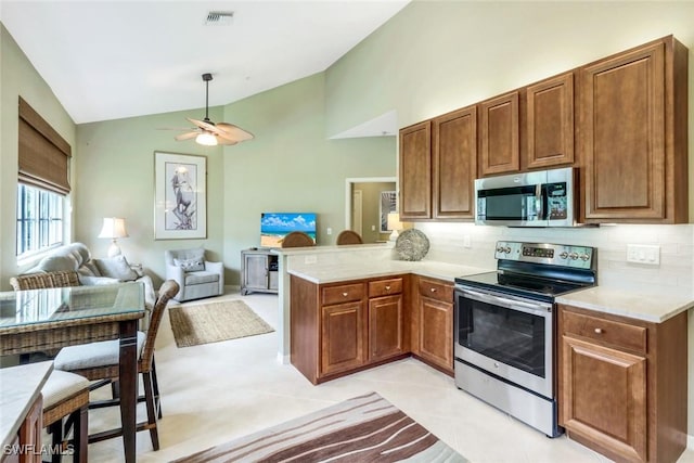 24320 Sandpiper Isle Way Unit 202, Bonita Springs, FL 34134 - kitchen featuring stainless steel appliances, vaulted ceiling, a peninsula, decorative backsplash, and light countertops