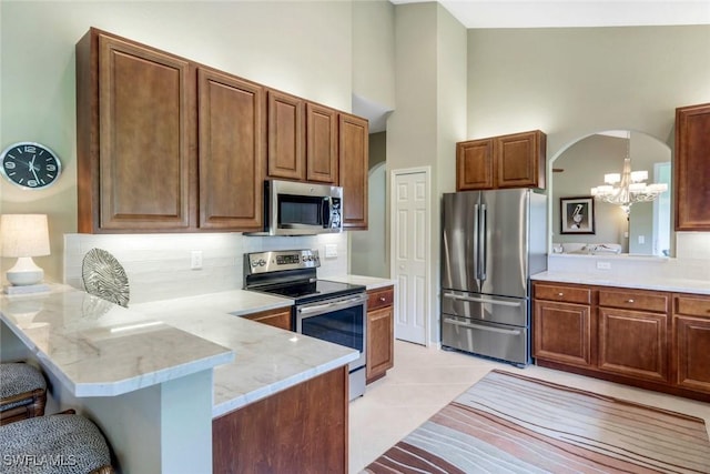 24320 Sandpiper Isle Way Unit 202, Bonita Springs, FL 34134 - kitchen with stainless steel appliances, a peninsula, arched walkways, a kitchen bar, and a chandelier