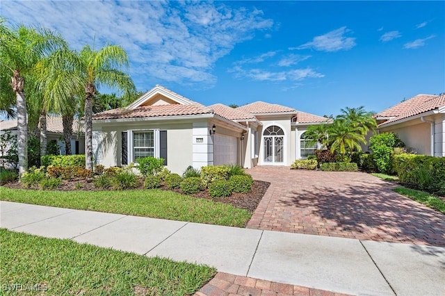 28864 Yellow Fin Trl, Bonita Springs, FL 34135 - mediterranean / spanish home featuring an attached garage, stucco siding, a tile roof, and decorative driveway