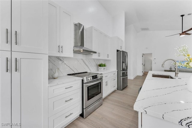 221 Saint James Way, Naples, FL 34104 - kitchen with wall chimney exhaust hood, appliances with stainless steel finishes, white cabinets, backsplash, and light stone counters