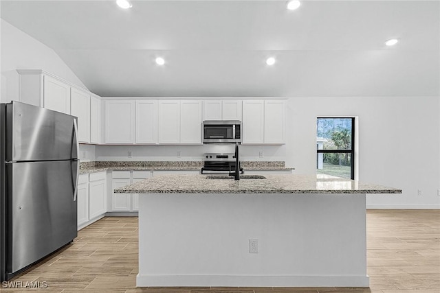 735 La Plata Ave, Lehigh Acres, FL 33974 - kitchen featuring stainless steel appliances, vaulted ceiling, light stone counters, white cabinetry, and light wood-style floors