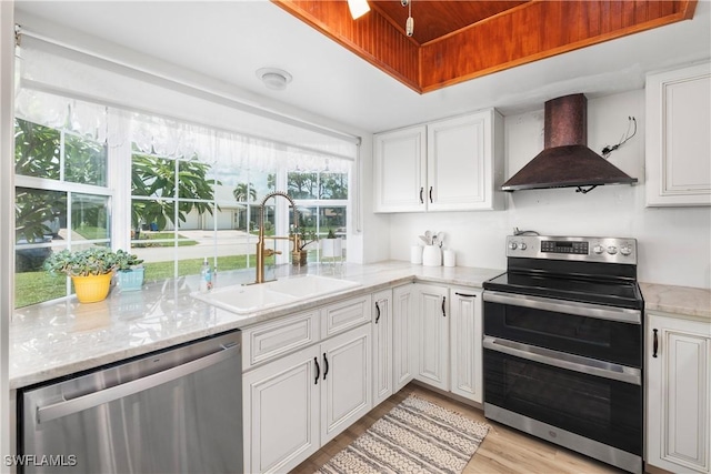 6340 P G A Dr, North Fort Myers, FL 33917 - kitchen featuring wall chimney range hood, stainless steel appliances, white cabinetry, light wood-style flooring, and light stone countertops