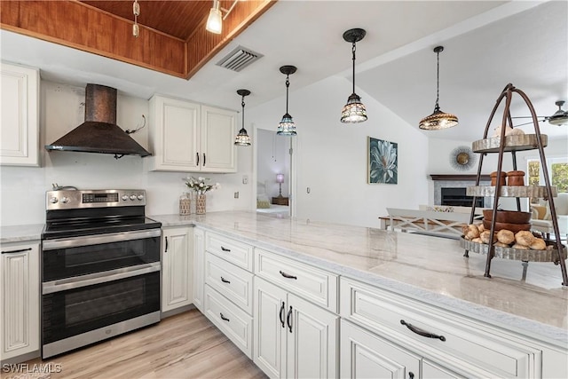 6340 P G A Dr, North Fort Myers, FL 33917 - kitchen featuring double oven range, wall chimney range hood, white cabinets, a fireplace, and vaulted ceiling