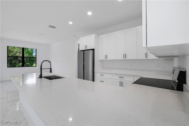 3644 35th Ave NE, Naples, FL 34120 - kitchen with range, freestanding refrigerator, recessed lighting, light stone counters, and white cabinetry