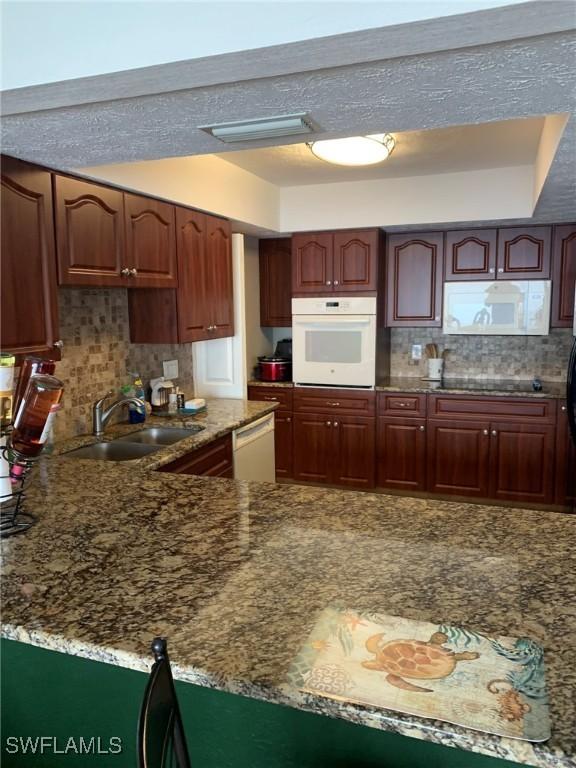 4015 SE 20th Pl Unit 503, Cape Coral, FL 33904 - kitchen with white appliances, decorative backsplash, and dark stone counters