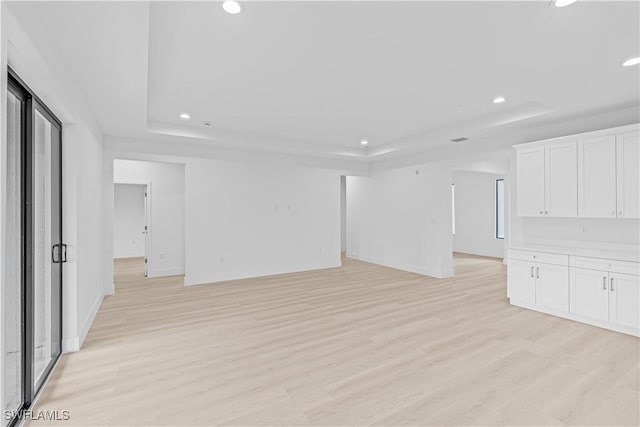 1061 Sunrise Blvd, Lehigh Acres, FL 33974 - unfurnished living room with a tray ceiling, recessed lighting, and light wood-type flooring