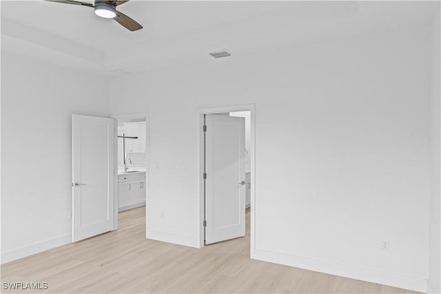 1061 Sunrise Blvd, Lehigh Acres, FL 33974 - unfurnished bedroom featuring light wood finished floors, ensuite bath, a spacious closet, and a ceiling fan
