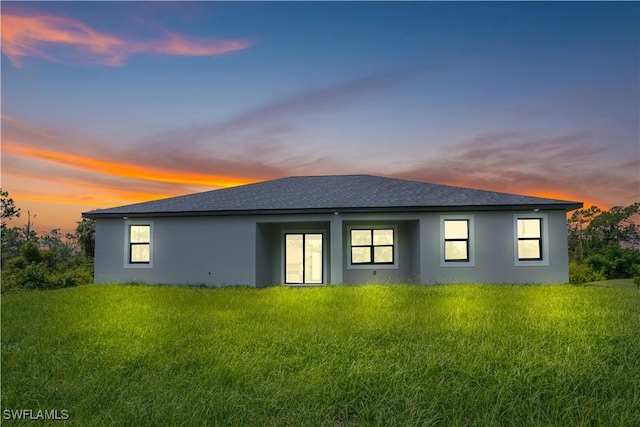 1061 Sunrise Blvd, Lehigh Acres, FL 33974 - back of property at dusk with stucco siding and a shingled roof