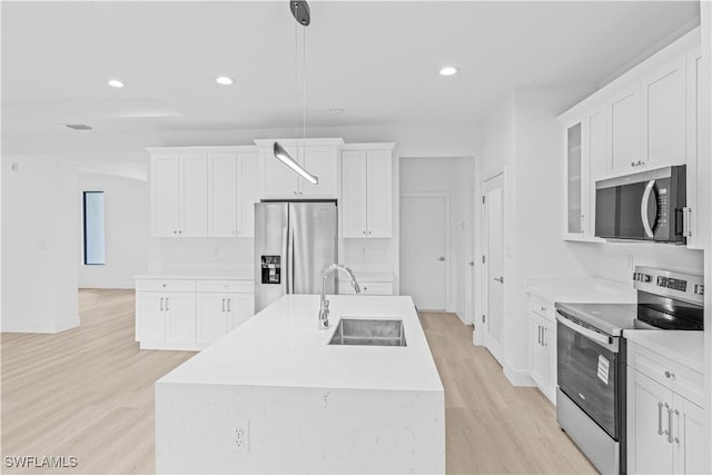 1061 Sunrise Blvd, Lehigh Acres, FL 33974 - kitchen featuring stainless steel appliances, light wood-style floors, a center island with sink, recessed lighting, and white cabinets