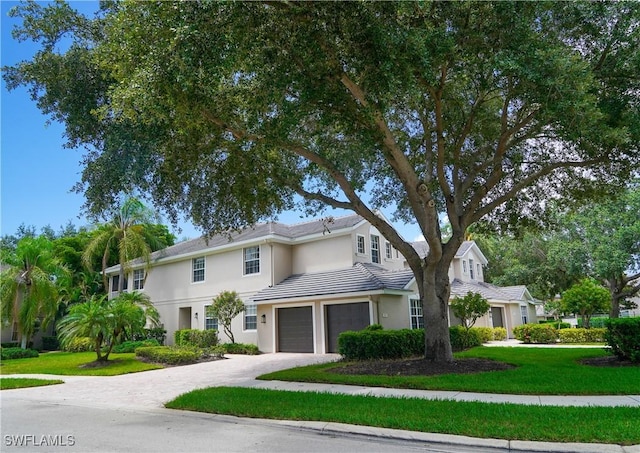 7120 Timberland Cir Unit 101, Naples, FL 34109 - view of front facade with an attached garage, stucco siding, driveway, a front lawn, and a tiled roof