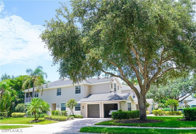7120 Timberland Cir Unit 101, Naples, FL 34109 - view of front of home featuring driveway, an attached garage, a front lawn, and stucco siding