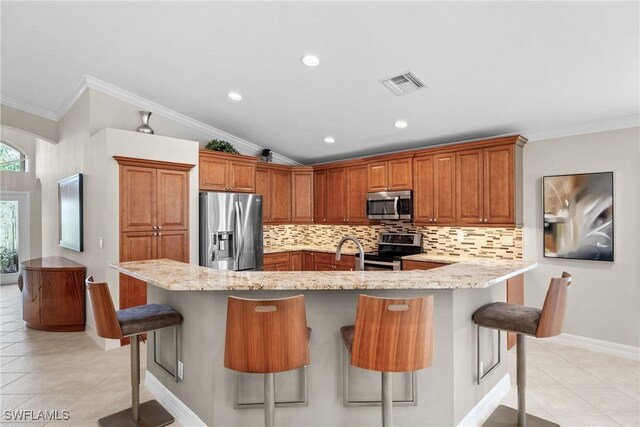 2434 Butterfly Palm Dr, Naples, FL 34119 - kitchen with appliances with stainless steel finishes, crown molding, tasteful backsplash, light tile patterned floors, and a kitchen breakfast bar