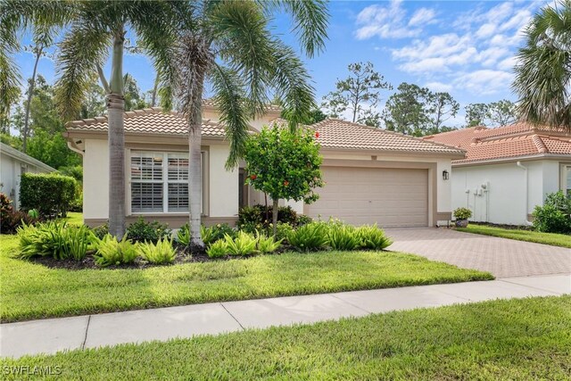 2434 Butterfly Palm Dr, Naples, FL 34119 - view of front of home featuring an attached garage, driveway, stucco siding, a tiled roof, and a front yard