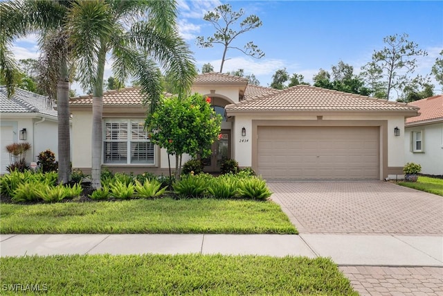 2434 Butterfly Palm Dr, Naples, FL 34119 - mediterranean / spanish-style house featuring stucco siding, a tiled roof, an attached garage, and decorative driveway