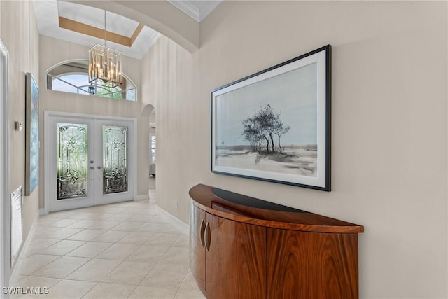 2434 Butterfly Palm Dr, Naples, FL 34119 - foyer featuring arched walkways, a chandelier, crown molding, light tile patterned floors, and french doors