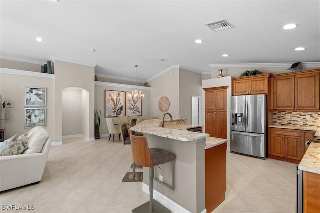 2434 Butterfly Palm Dr, Naples, FL 34119 - kitchen featuring stainless steel fridge, arched walkways, ornamental molding, brown cabinetry, and a chandelier