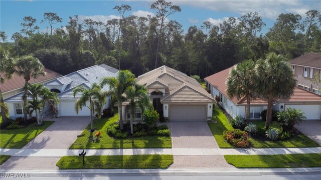 2434 Butterfly Palm Dr, Naples, FL 34119 - view of front of house featuring decorative driveway, an attached garage, a tile roof, stucco siding, and a front yard