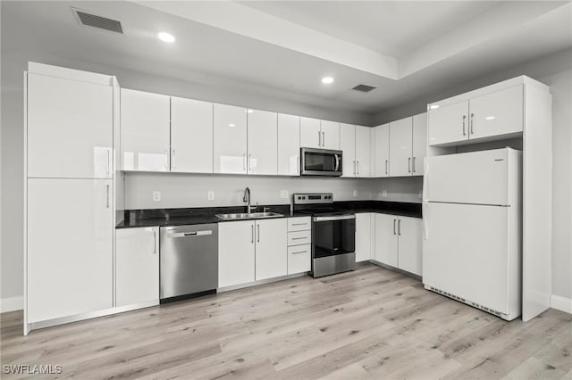 3006 72nd St W, Lehigh Acres, FL 33971 - kitchen featuring stainless steel appliances, recessed lighting, dark countertops, light wood-style floors, and white cabinetry