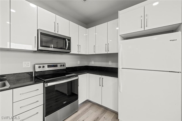 3006 72nd St W, Lehigh Acres, FL 33971 - kitchen featuring appliances with stainless steel finishes, white cabinets, light wood-type flooring, and dark countertops