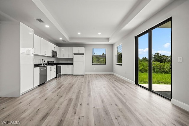 3006 72nd St W, Lehigh Acres, FL 33971 - kitchen with stainless steel appliances, light wood-type flooring, a raised ceiling, white cabinets, and recessed lighting