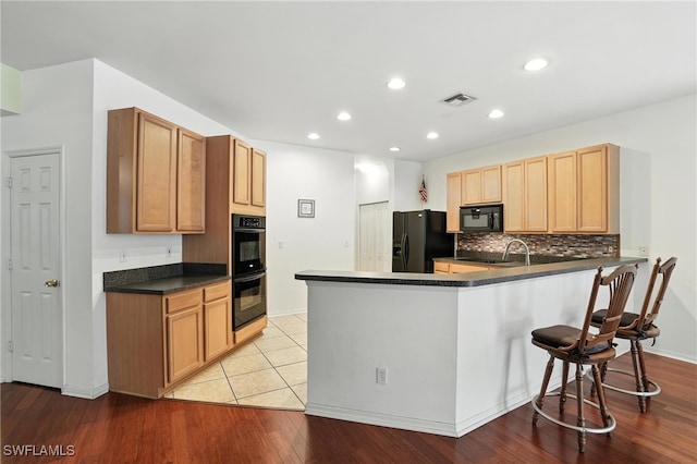 10043 Winding River Rd, Punta Gorda, FL 33950 - kitchen with black appliances, a peninsula, dark countertops, decorative backsplash, and light wood-style flooring