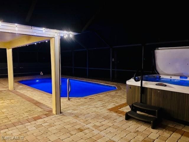 2116 NW 24th Ave, Cape Coral, FL 33993 - pool at night featuring an outdoor pool, a patio area, a hot tub, and glass enclosure