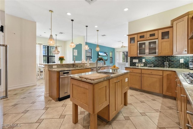 3917 La Vida Way, Cape Coral, FL 33993 - kitchen with a kitchen island with sink, plenty of natural light, decorative backsplash, light stone counters, and recessed lighting
