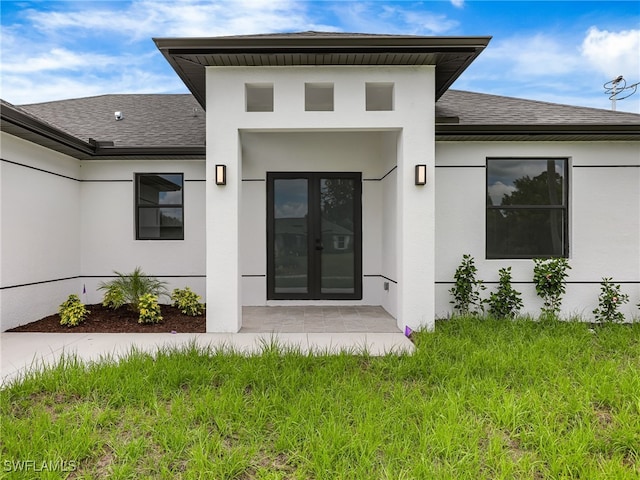 3219 43rd St W, Lehigh Acres, FL 33971 - property entrance with a shingled roof, stucco siding, and french doors