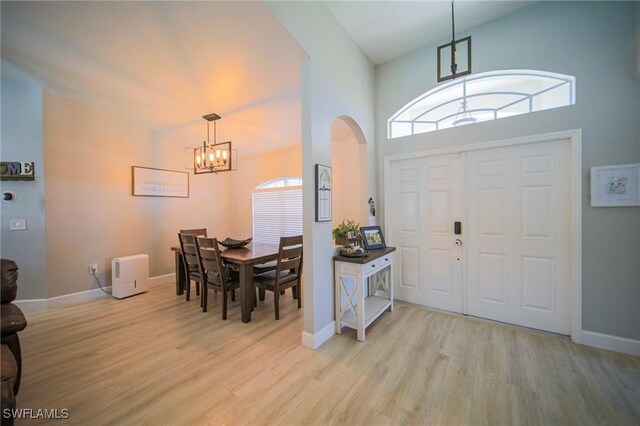 823 Portland St E, Lehigh Acres, FL 33974 - foyer entrance with a chandelier, arched walkways, light wood finished floors, plenty of natural light, and high vaulted ceiling