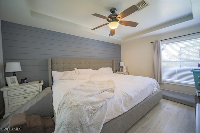 823 Portland St E, Lehigh Acres, FL 33974 - bedroom featuring a tray ceiling, wood finished floors, ceiling fan, and wooden walls