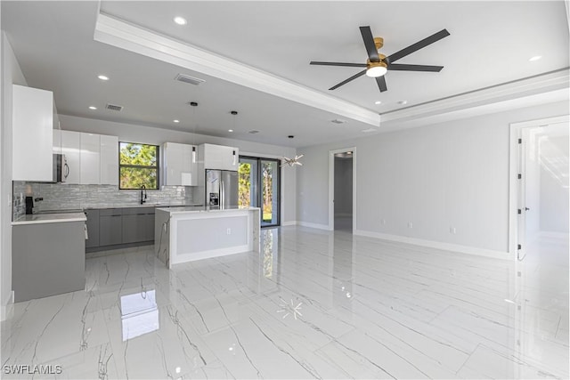 3306 40th St W, Lehigh Acres, FL 33971 - kitchen featuring stainless steel appliances, a tray ceiling, open floor plan, a kitchen island, and modern cabinets