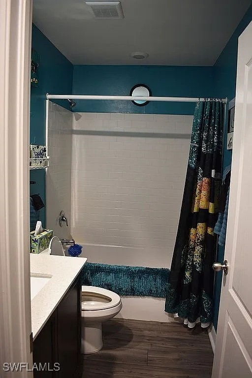 845 Lochman Dr, Fort Myers, FL 33913 - full bath featuring wood finished floors, vanity, and shower / tub combo with curtain