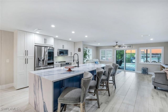 4911 Esplanade St, Bonita Springs, FL 34134 - kitchen featuring appliances with stainless steel finishes, open floor plan, a center island with sink, light stone countertops, and recessed lighting