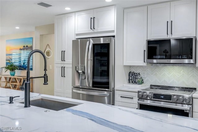 4911 Esplanade St, Bonita Springs, FL 34134 - kitchen with stainless steel appliances, light stone counters, tasteful backsplash, white cabinetry, and recessed lighting