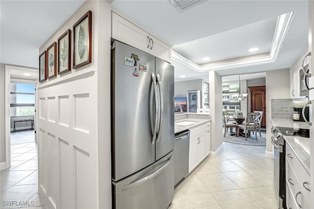 300 S Collier Blvd Unit 303, Marco Island, FL 34145 - kitchen featuring appliances with stainless steel finishes, light tile patterned floors, white cabinetry, a raised ceiling, and recessed lighting