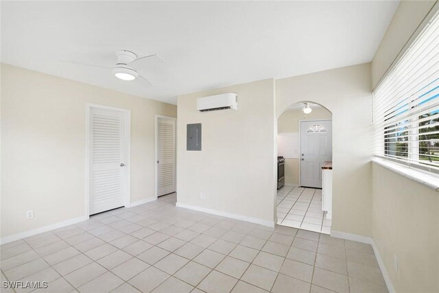 527 Goodland Drive W, Goodland, FL 34140 - empty room featuring a wall mounted air conditioner, electric panel, arched walkways, ceiling fan, and light tile patterned flooring
