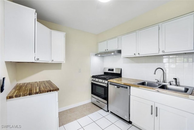 527 Goodland Drive W, Goodland, FL 34140 - kitchen featuring stainless steel appliances, under cabinet range hood, tasteful backsplash, white cabinets, and light tile patterned floors