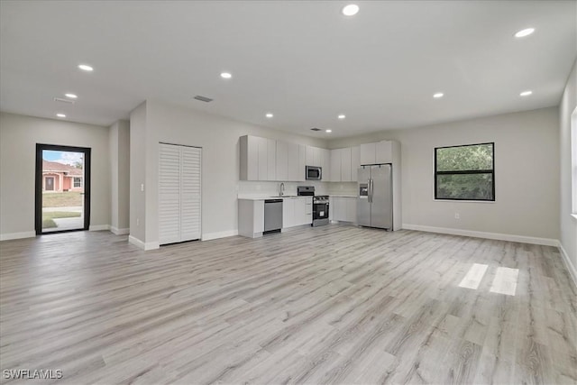 unfurnished living room featuring plenty of natural light, light wood finished floors, and recessed lighting