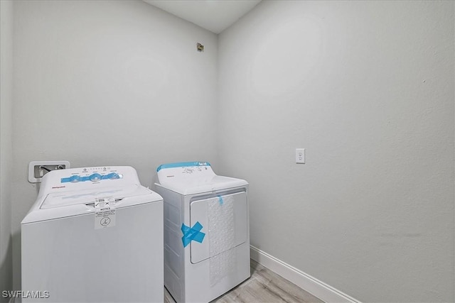 laundry area featuring washing machine and clothes dryer and light wood-type flooring