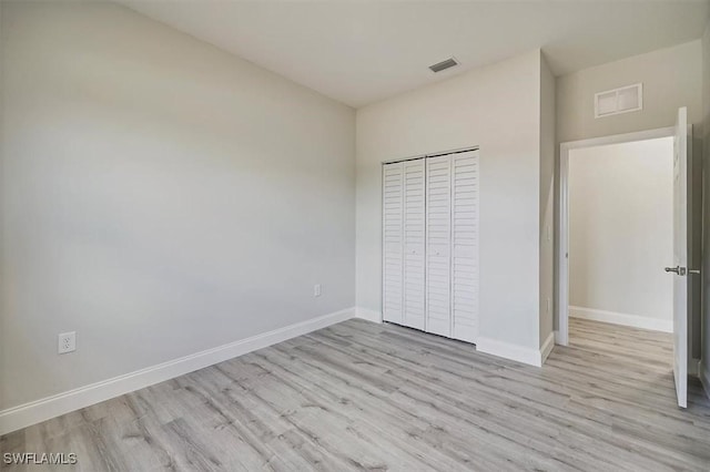 unfurnished bedroom with wood finished floors and a closet