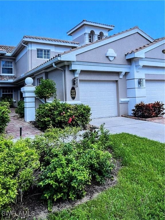 3975 Deer Crossing Ct Unit 102, Naples, FL 34114 - view of front of property featuring stucco siding, a garage, concrete driveway, and a tiled roof