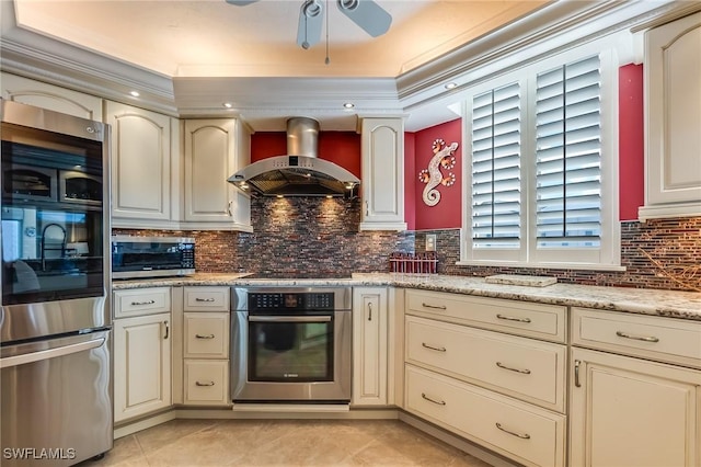 4745 Estero Blvd Unit 302, Fort Myers Beach, FL 33931 - kitchen with appliances with stainless steel finishes, wall chimney range hood, cream cabinetry, ceiling fan, and tasteful backsplash