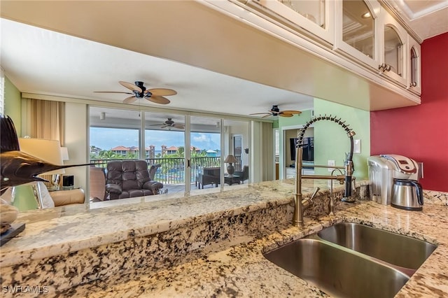 4745 Estero Blvd Unit 302, Fort Myers Beach, FL 33931 - kitchen with ceiling fan, light stone counters, and glass insert cabinets