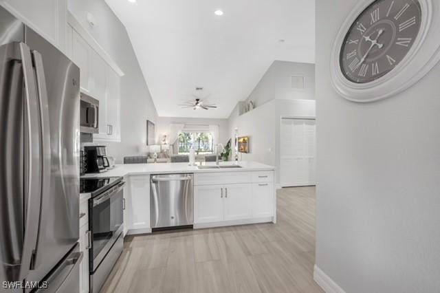 3505 Avion Woods Ct Unit 902, Naples, FL 34104 - kitchen with stainless steel appliances, white cabinets, a peninsula, a ceiling fan, and vaulted ceiling