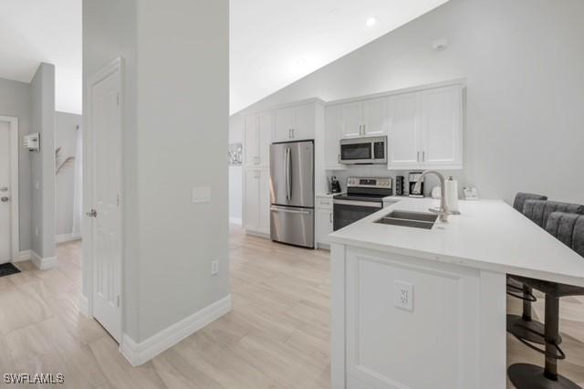 3505 Avion Woods Ct Unit 902, Naples, FL 34104 - kitchen featuring appliances with stainless steel finishes, a kitchen bar, a peninsula, white cabinets, and light countertops