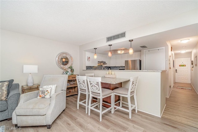 400 Lenell Rd Unit 207, Fort Myers Beach, FL 33931 - kitchen with freestanding refrigerator, light wood-style floors, a peninsula, a breakfast bar, and pendant lighting
