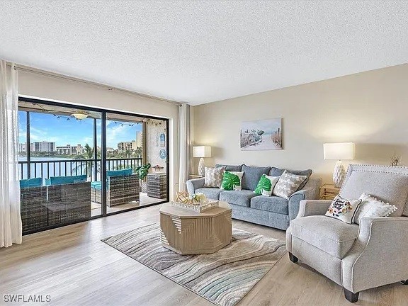 400 Lenell Rd Unit 207, Fort Myers Beach, FL 33931 - living room with wood finished floors, a textured ceiling, and a water view